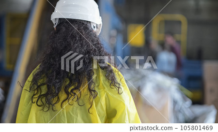 Black-haired woman in helmet walks along waste sorting plant Black-haired woman in helmet walks along waste sorting plant 105801469
