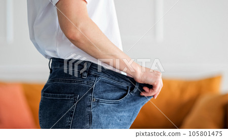 Slim woman with lost weight puts on former spacious jeans Slim woman with lost weight puts on former spacious jeans 105801475