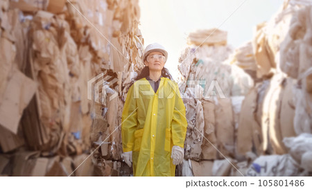 Long-haired woman walks past pile of trash at waste factory 105801486