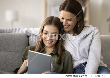 Cheerful mom and schoolgirl daughter in glasses using online service 105801510