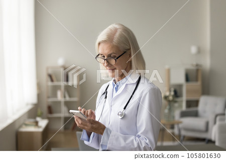 Mature doctor checking appointment schedule on professional app 105801630
