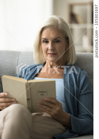 Focused older pensioner woman excited with book story reading paper 105801697