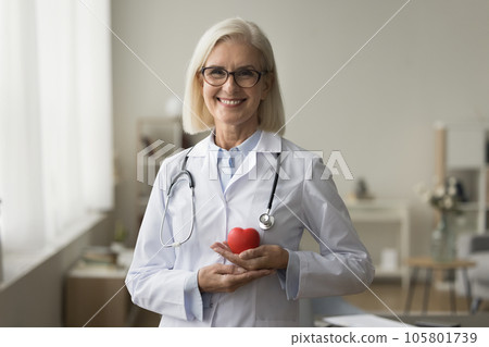 Happy senior doctor woman holding red heart shape at chest 105801739