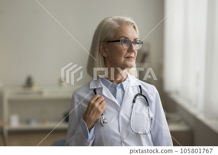 Serious senior medical practitioner in glasses and uniform looking away Serious senior medical practitioner in glasses and uniform looking away 105801767