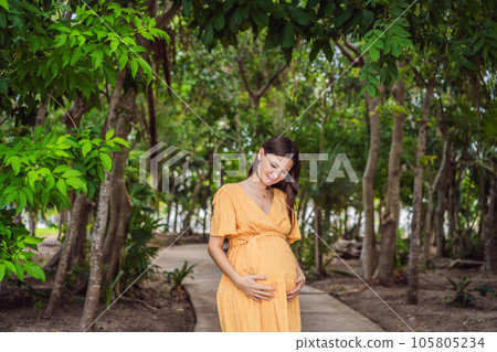 A serene and radiant pregnant woman after 40, surrounded by nature's beauty in the park, cherishing the journey of motherhood with a glowing smile A serene and radiant pregnant woman after 40, surrounded by nature's beauty in the park, cherishing the journey of motherhood with a glowing smile 105805234