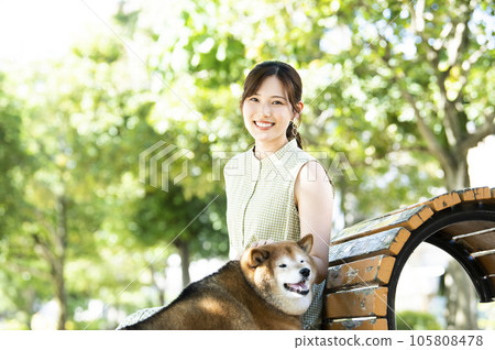 一名年輕女子和一隻柴犬在公園長椅上休息 一名年輕女子和一隻柴犬在公園長椅上休息 105808478