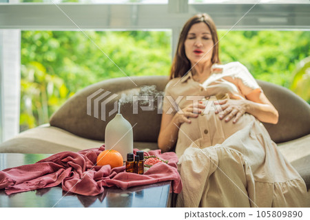 A serene moment captured as a pregnant woman after 40 embraces the soothing benefits of aroma oils and an aroma diffuser, enhancing her pregnancy journey with relaxation and tranquility A serene moment captured as a pregnant woman after 40 embraces the soothing benefits of aroma oils and an aroma diffuser, enhancing her pregnancy journey with relaxation and tranquility 105809890
