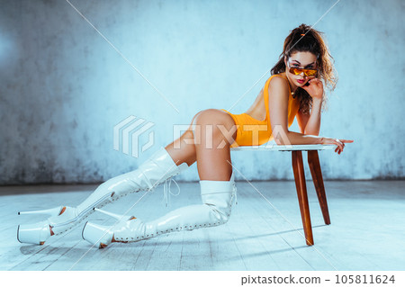 Young woman dancer posing in bright white interior with table 105811624