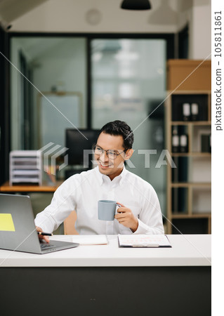 Confident Asian man with a smile standing holding notepad and tablet at the office. Confident Asian man with a smile standing holding notepad and tablet at the office. 105811861