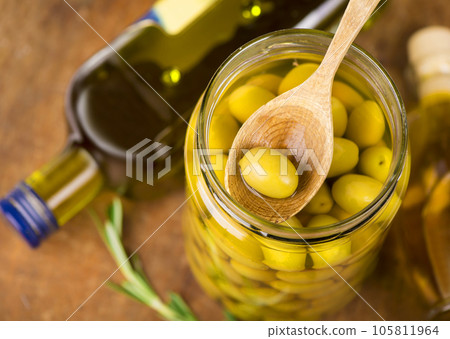 Close up green olives in wooden spoon, rosemary on a wooden background 105811964