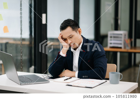 Overworked young Asian businessman office worker suffering from neck pain after had a long day at her office desk. office syndrome concept. Overworked young Asian businessman office worker suffering from neck pain after had a long day at her office desk. office syndrome concept. 105811980