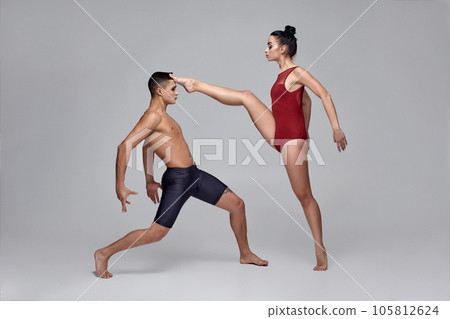 The couple of an athletic modern ballet dancers are posing against a gray studio background. 105812624