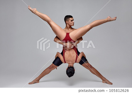 The couple of an athletic modern ballet dancers are posing against a gray studio background. 105812626