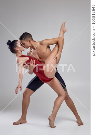 The couple of an athletic modern ballet dancers are posing against a gray studio background. The couple of an athletic modern ballet dancers are posing against a gray studio background. 105812643