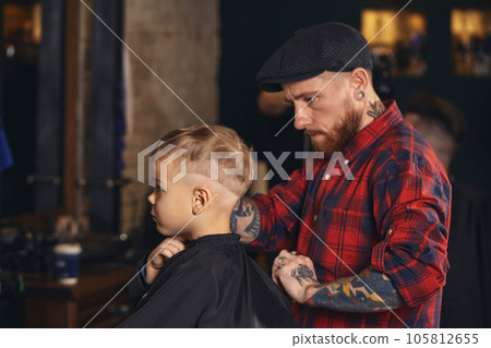 Caucasian boy getting haircut in barbershop indoor Caucasian boy getting haircut in barbershop indoor 105812655