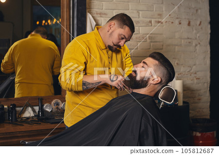 Client with big black beard during beard shaving in barber shop 105812687