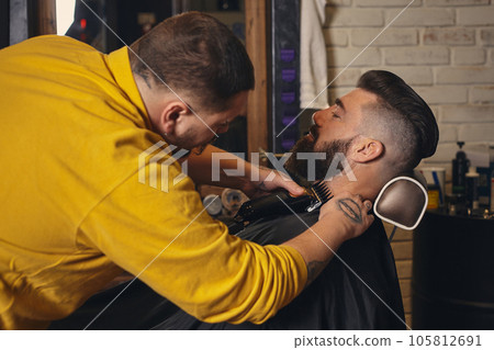 Client with big black beard during beard shaving in barber shop 105812691