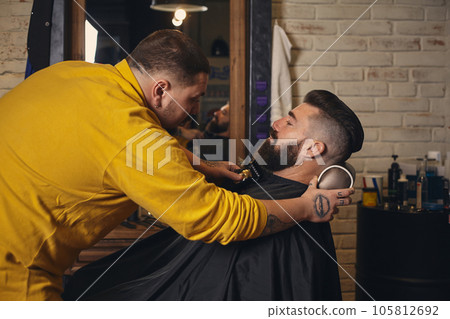 Client with big black beard during beard shaving in barber shop 105812692