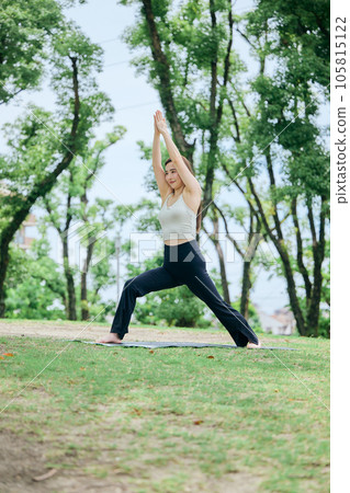 Woman doing warrior pose 1 in yoga outside Woman doing warrior pose 1 in yoga outside 105815122