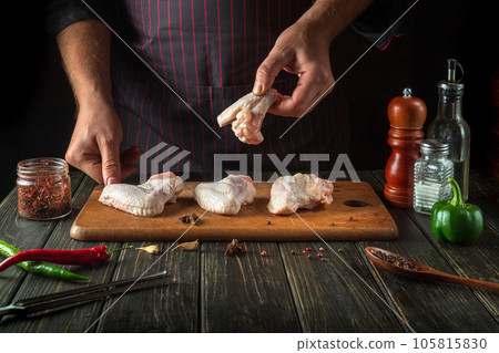 Cooking chicken nugget by the cookn hands in the restaurant kitchen with vegetables and spices. Space for advertising on a dark background 105815830