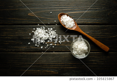 Coarse sea salt in a wooden spoon and on a vintage table. Traditional medicine concept. 105815867