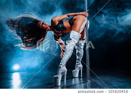Young woman pole dancing on dark background with blue smoke 105820458