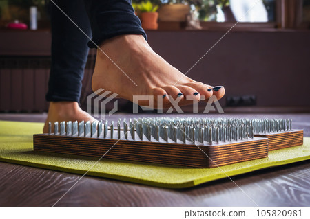 A woman practicing yoga, performs an exercise on a sadhu board with nails, a concept on the topic of a healthy lifestyle and hardening of the body 105820981