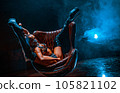 Young bdsm style woman dancer posing in chair in dark interior 105821102