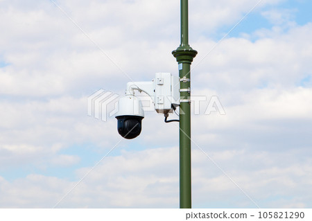 outdoor security dome video camera, street video camera on lamppost on cloudy sky, back view 105821290