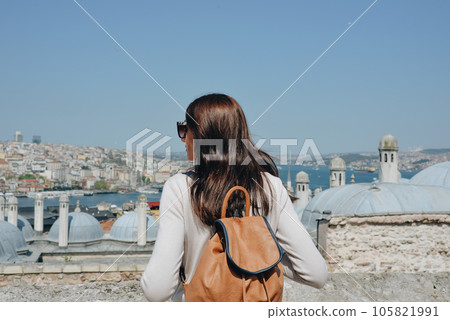 A young traveler with a backpack on her back looks at the landscape from the Suleymaniye Mosque on a sunny day in Istanbul A young traveler with a backpack on her back looks at the landscape from the Suleymaniye Mosque on a sunny day in Istanbul 105821991