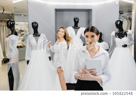 Attractive bridal shop owner women use digital tablet help customer choosing wedding gown at the store 105822548