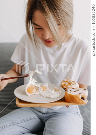 Vertical photo of woman eating fried eggs as breakfast. Vertical photo of woman eating fried eggs as breakfast. 105825240