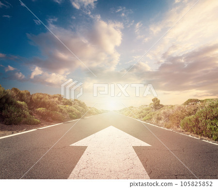 Success concept on an open road with white arrow at sunset sky clouds 105825852