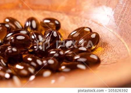 Herbal capsules from medicinal cannabis plant. CBD pills in wooden bowl. Cannabidiol herb treatment. Macro shot 105826392