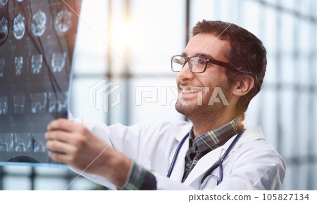 Doctor looking MRI picture on gray background Doctor looking MRI picture on gray background 105827134