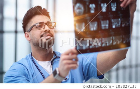 Confident doctor with x-ray picture in office Confident doctor with x-ray picture in office 105827135