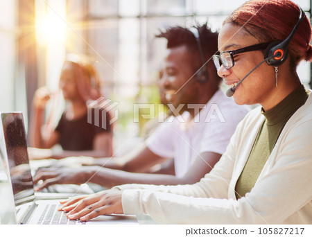 Smiling beautiful African American woman working in call center with diverse team 105827217