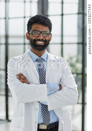 Portrait of a smiling male doctor standing in a hospital corridor 105827343