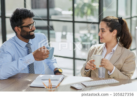 colleagues talking during lunch break while sitting at workplace 105827356