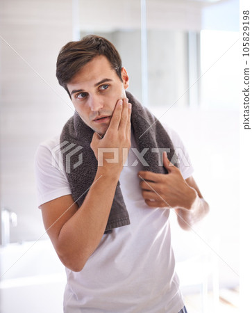 Skincare, shaving and face of man in bathroom for facial grooming, wellness and cosmetics at home. Health, dermatology and serious male person for hygiene, cleaning and hair removal with beauty cream 105829198
