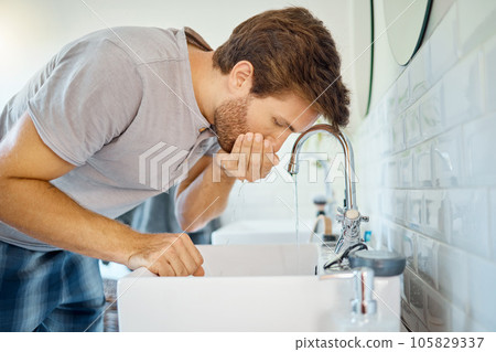 Man in bathroom, mouth wash and water with morning routine, health and wellness in home. Dental care, cleaning teeth and face with male grooming for fresh breath, hygiene and getting ready in house. Man in bathroom, mouth wash and water with morning routine, health and wellness in home. Dental care, cleaning teeth and face with male grooming for fresh breath, hygiene and getting ready in house. 105829337
