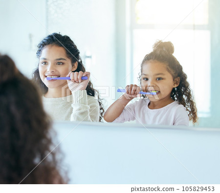 Brushing it right. Shot of a young mother and daughter brushing their teeth in a bathroom at home. Brushing it right. Shot of a young mother and daughter brushing their teeth in a bathroom at home. 105829453