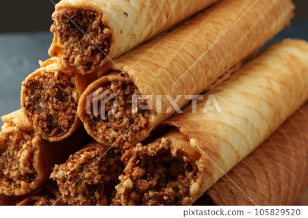 Waffle tubes with chocolate filling on wooden board Waffle tubes with chocolate filling on wooden board 105829520