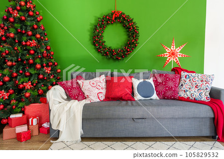 Christmas living room interior with sofa, Christmas tree and wreath on green background Christmas living room interior with sofa, Christmas tree and wreath on green background 105829532