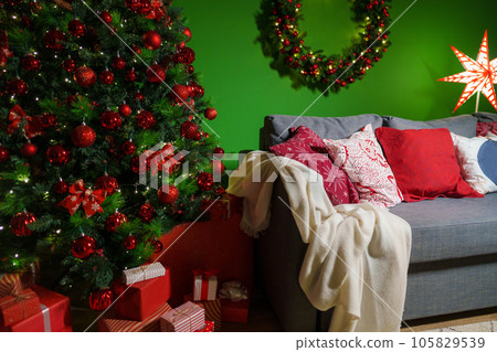 Christmas living room interior with sofa, Christmas tree and wreath on green background Christmas living room interior with sofa, Christmas tree and wreath on green background 105829539