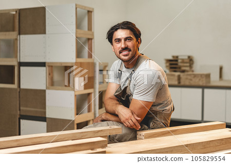 Portrait of young male carpenter standing in the wood workshop Portrait of young male carpenter standing in the wood workshop 105829554