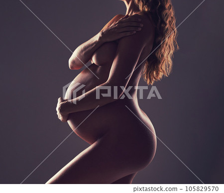 Body of pregnant woman, naked in studio and hand on stomach, aesthetic dark background at maternity reveal. Creative pregnancy photoshoot, art and nude mother holding belly with health and wellness. 105829570