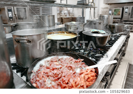 Food preparing in metal pots on the stove at professional kitchen Food preparing in metal pots on the stove at professional kitchen 105829683