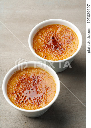Creme brulee with caramel in two white bowls on gray background 105829697