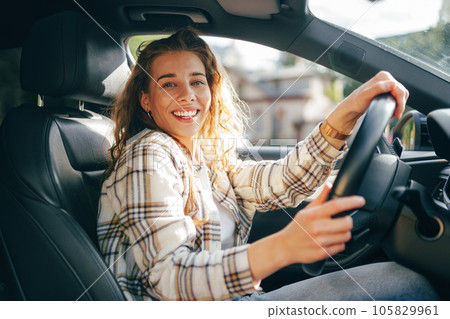 Happy smiling woman inside a car driving in the street Happy smiling woman inside a car driving in the street 105829961